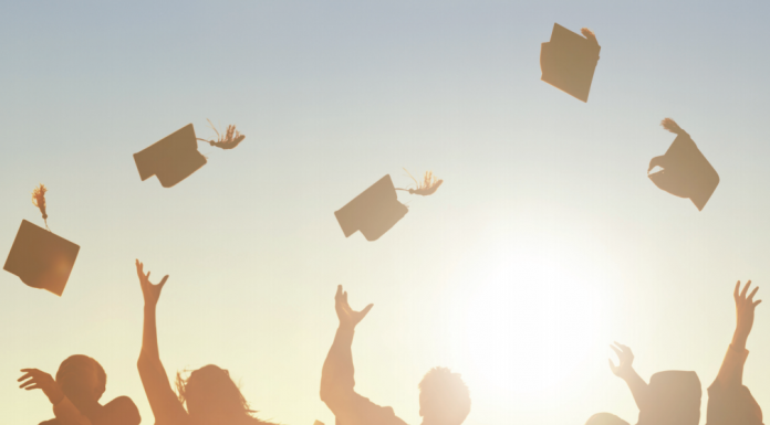 graduates throwing caps into air in sunset
