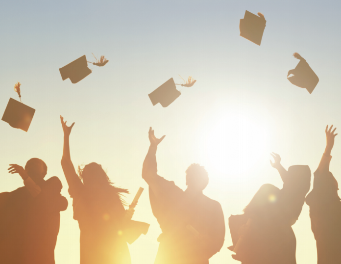 graduates throwing caps into air in sunset