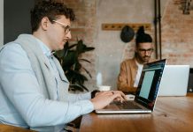 Two men type on laptops